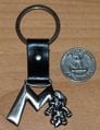 A metal keychain consisting of the letter "M", attached with Metal Mario at the right side